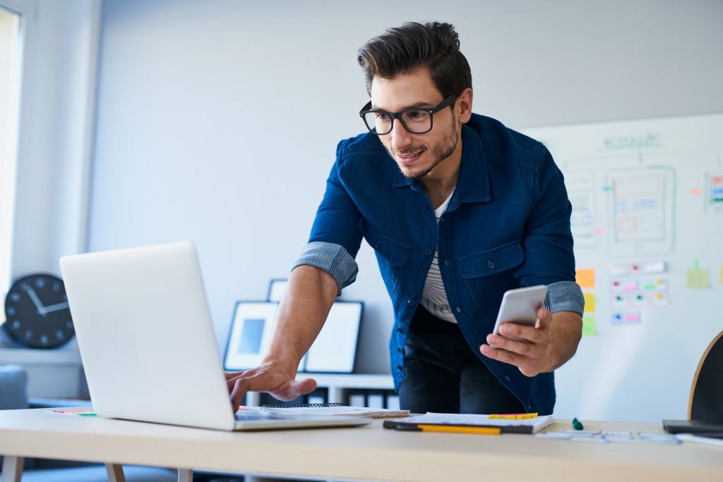 man using his phone and laptop