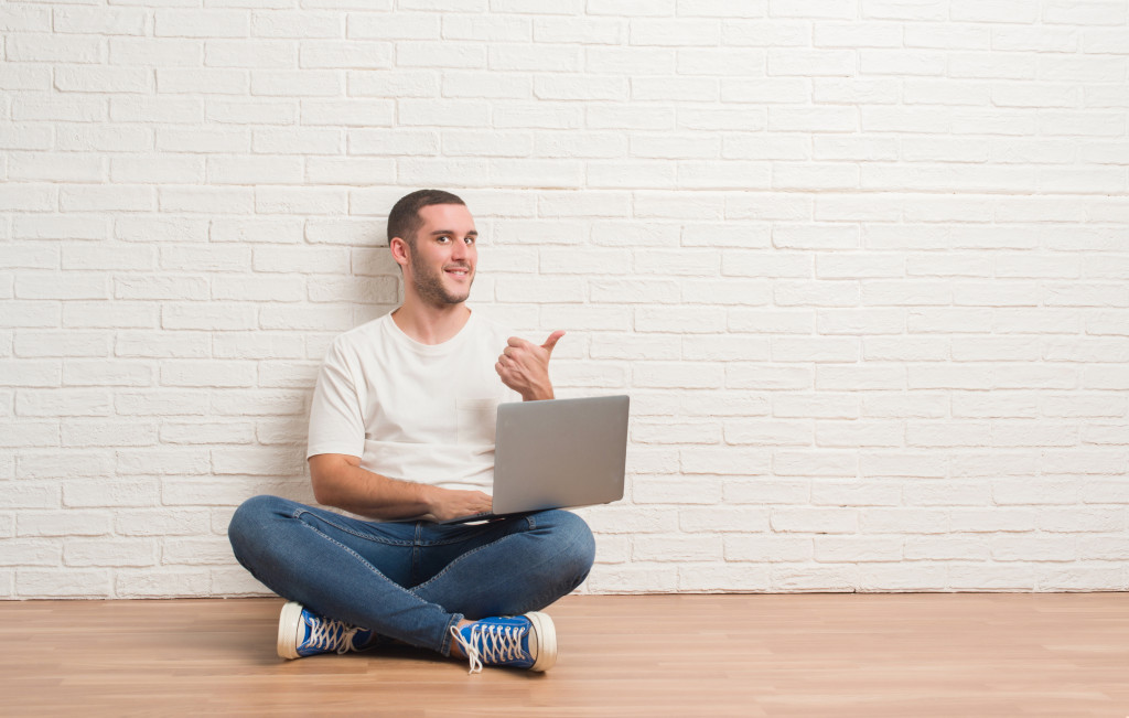 freelancer guy seated on the floor while using his laptop