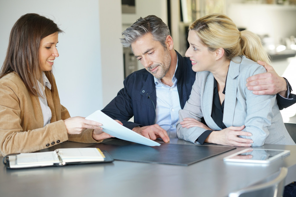 A real estate agent handing a contract to a couple