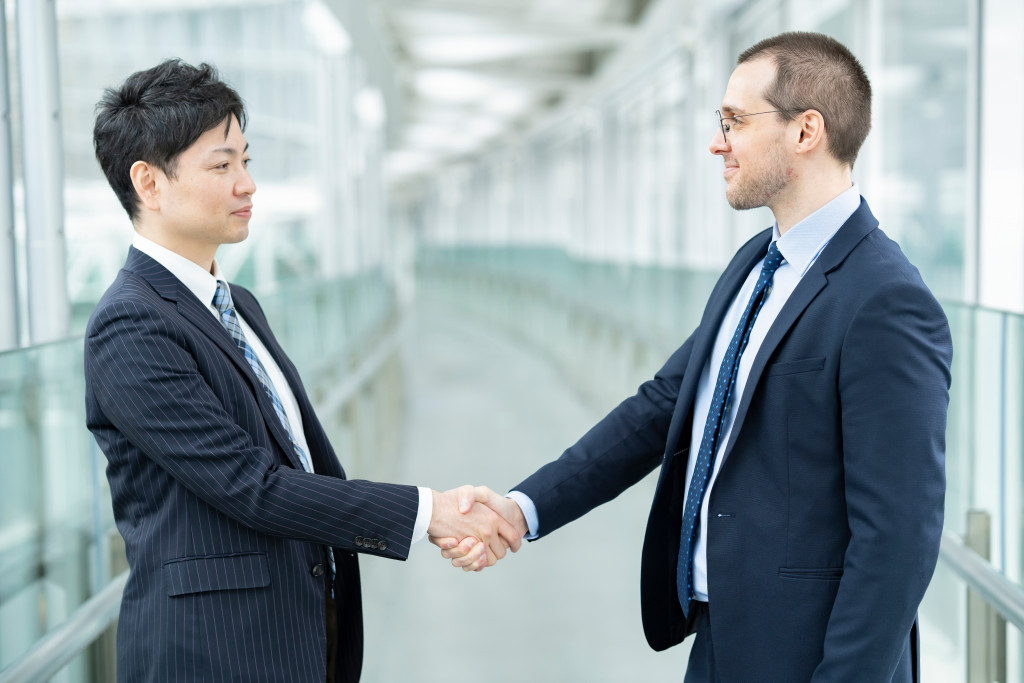 Two businessmen shaking hands in a clear hallway