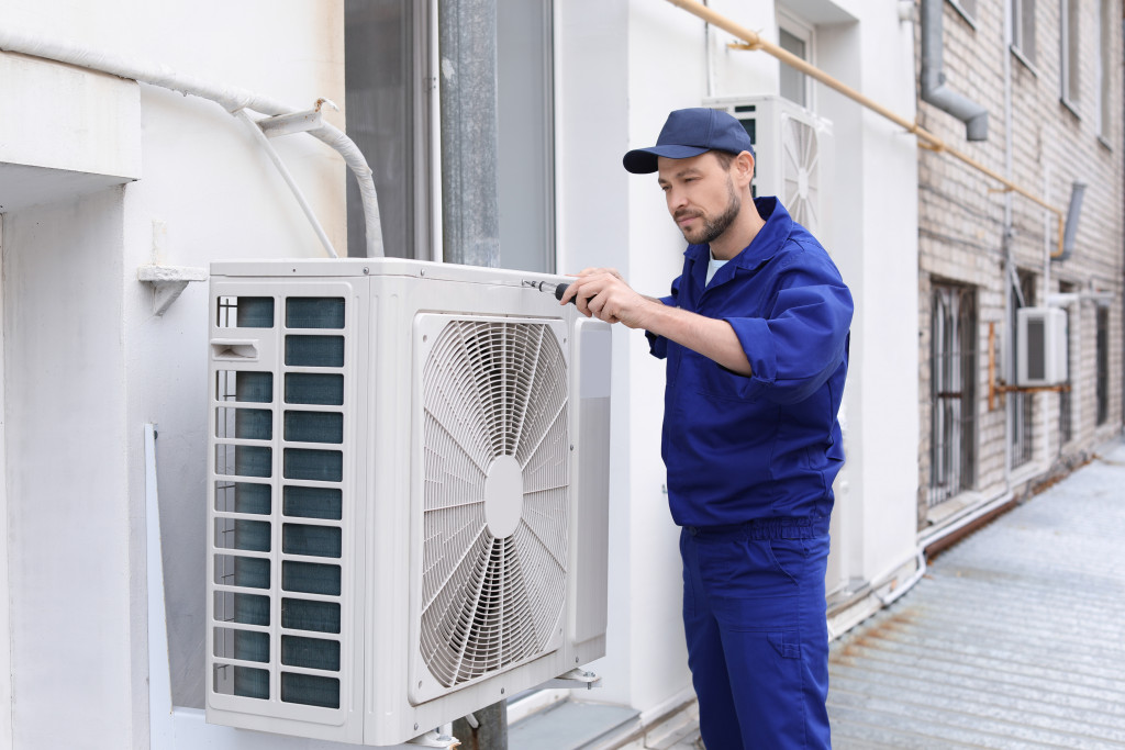 Mechanic repairing AC outdoor of a office 