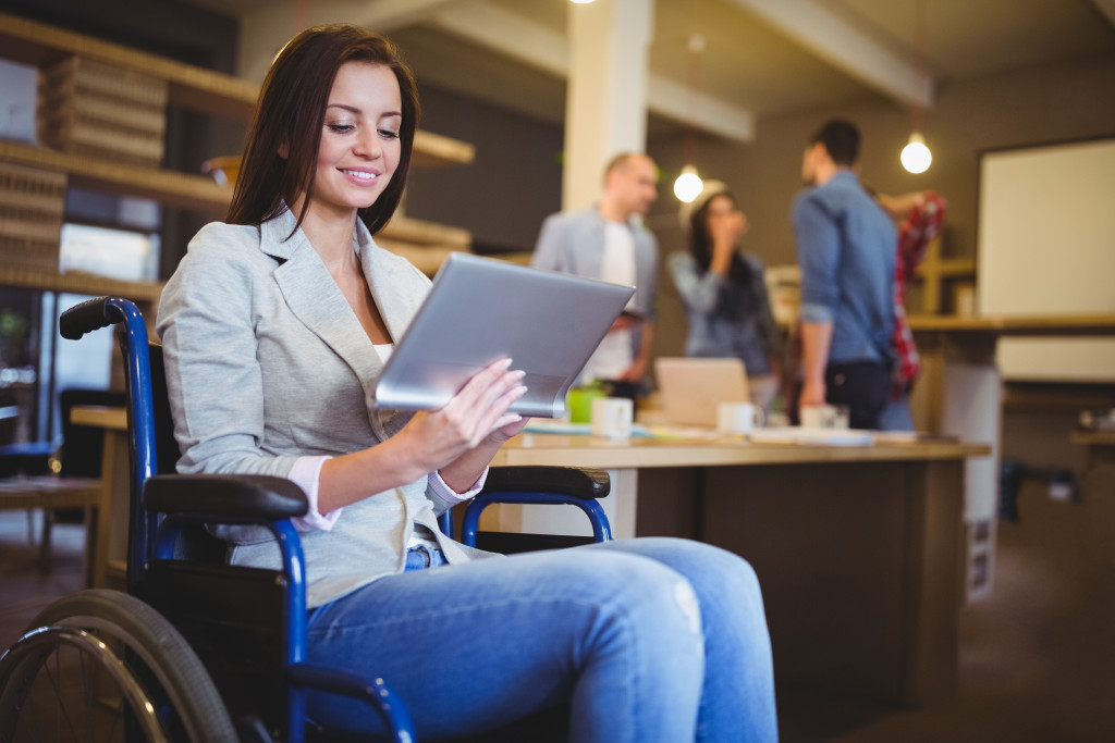 Disabled young businesswoman using digital tablet in creative office