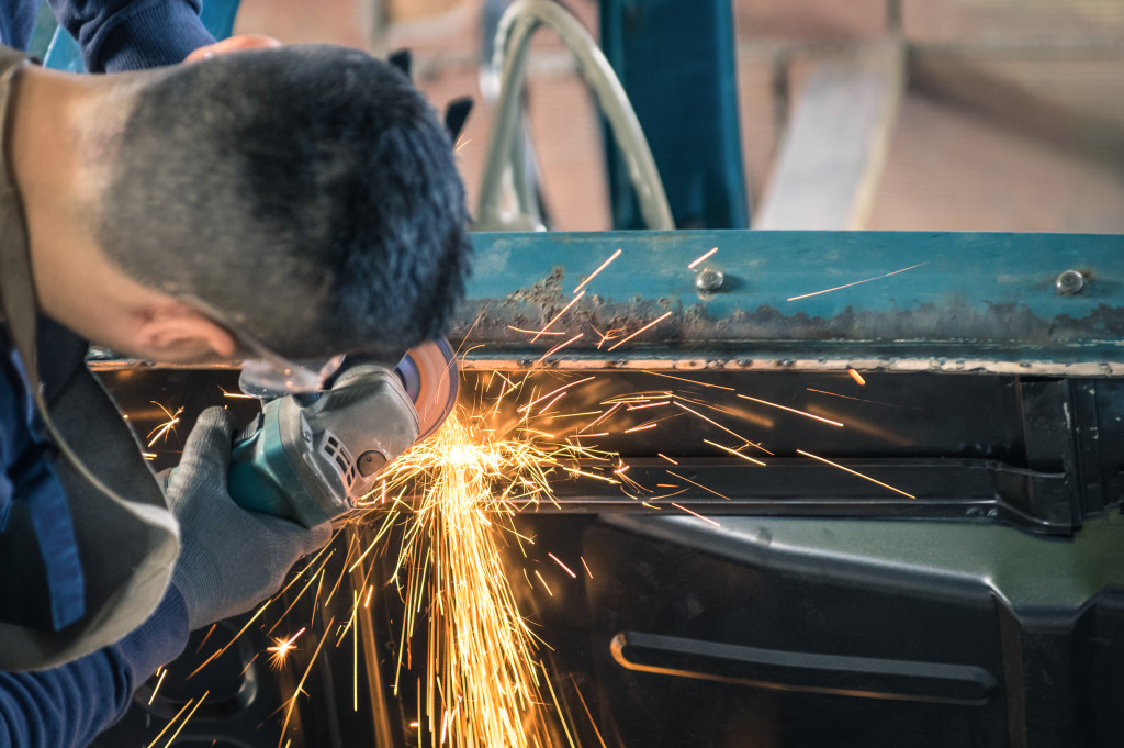 A welder uses a grinder to clean up a bad weld, making sparks fly