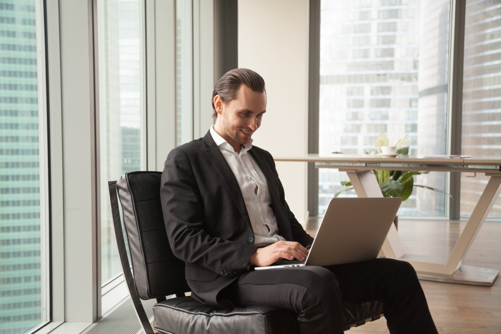 Businessman smiling while checking the laptop.