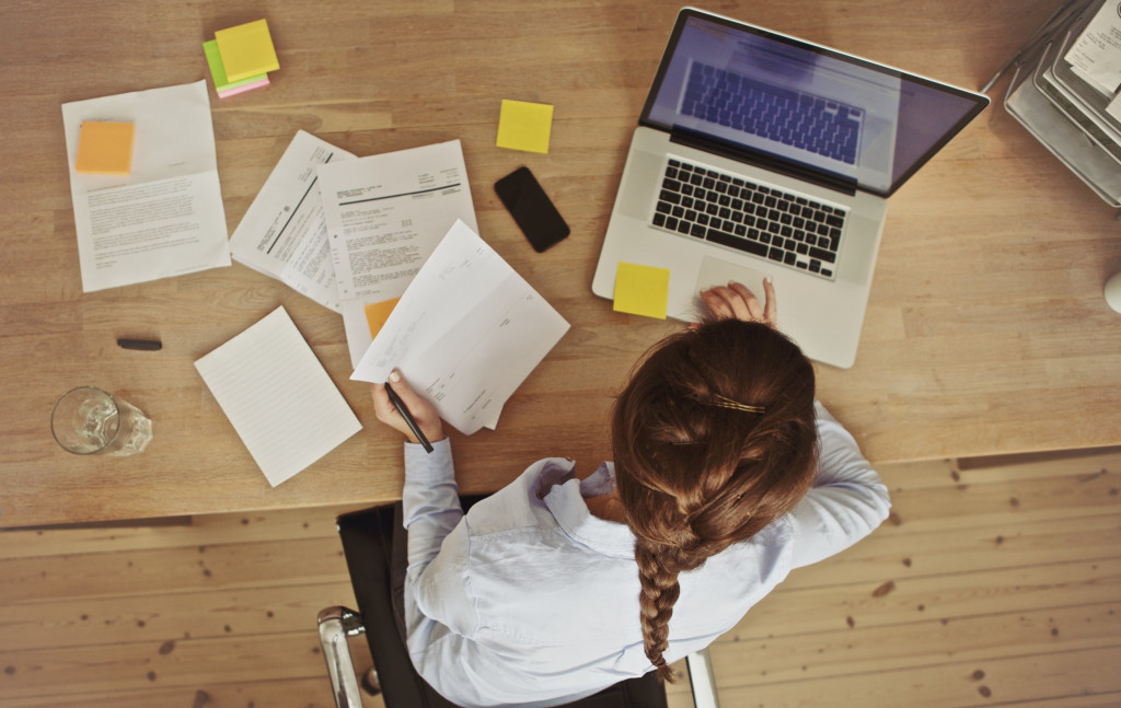 High-angle view of an young brunette working at her office desk with documents and laptop