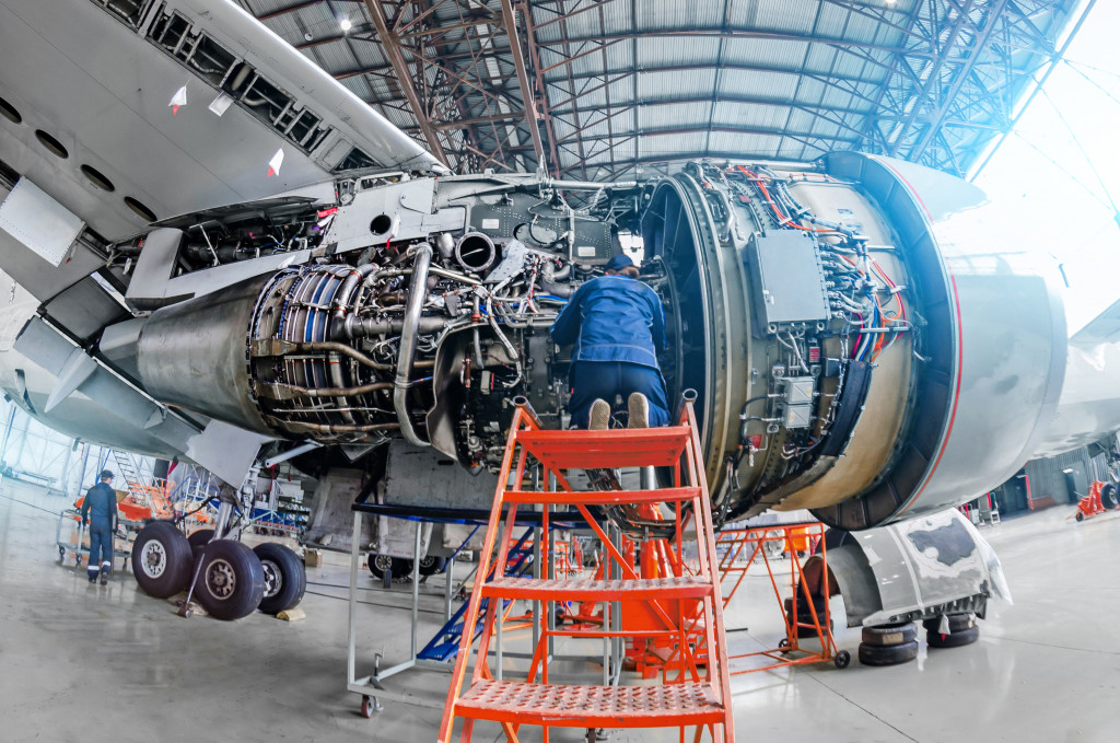 airplane maintenance workers checking and fixing airplane parked in hangar