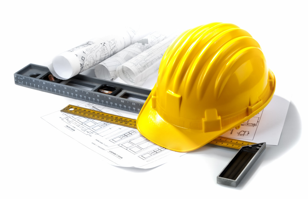 A hard hat with construction plans and rulers