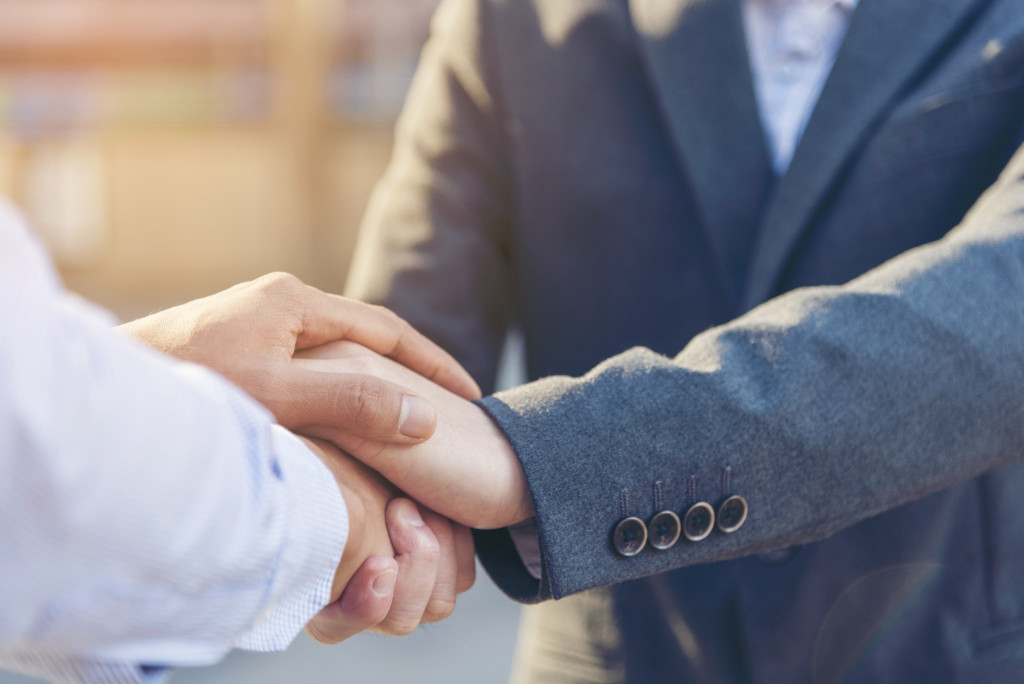 a lawyer's hand shaking and wrapping over an investor's hands