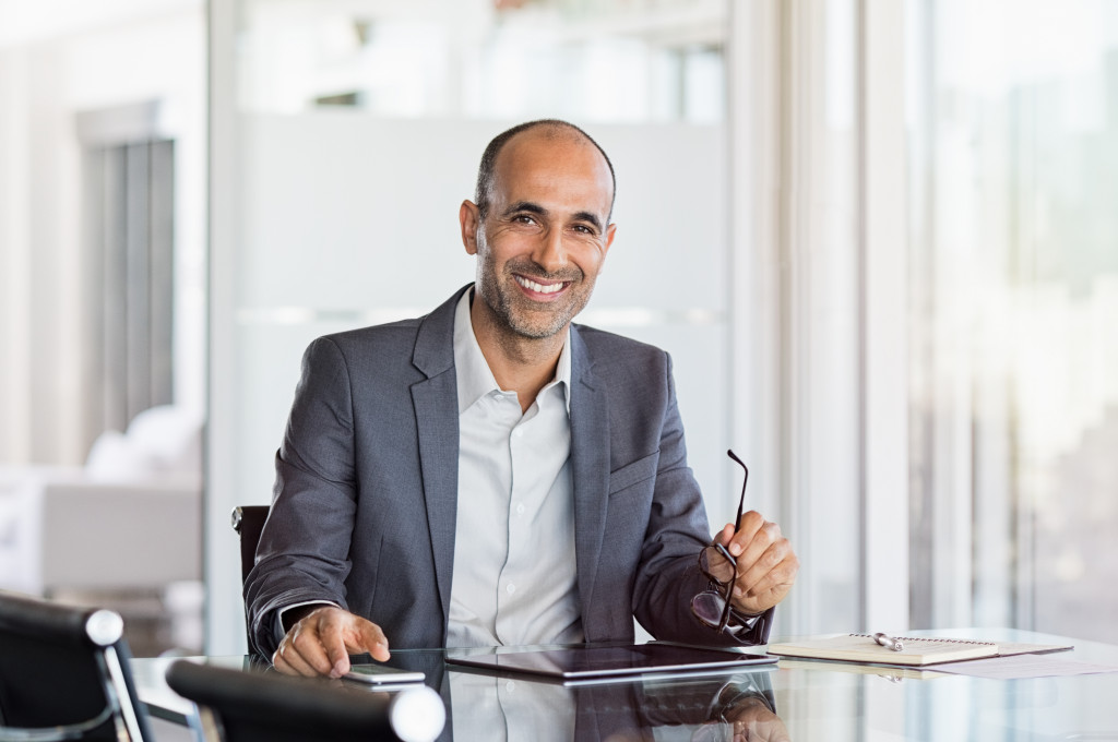 business man smiling holding his glasses and phone