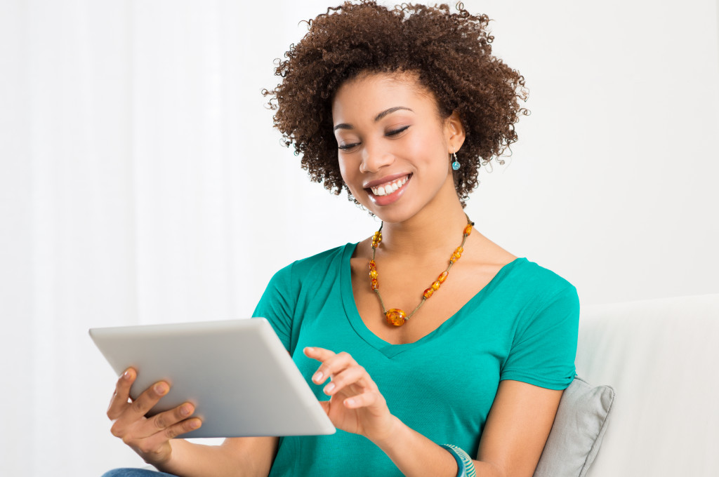 woman at home smiling using her tablet