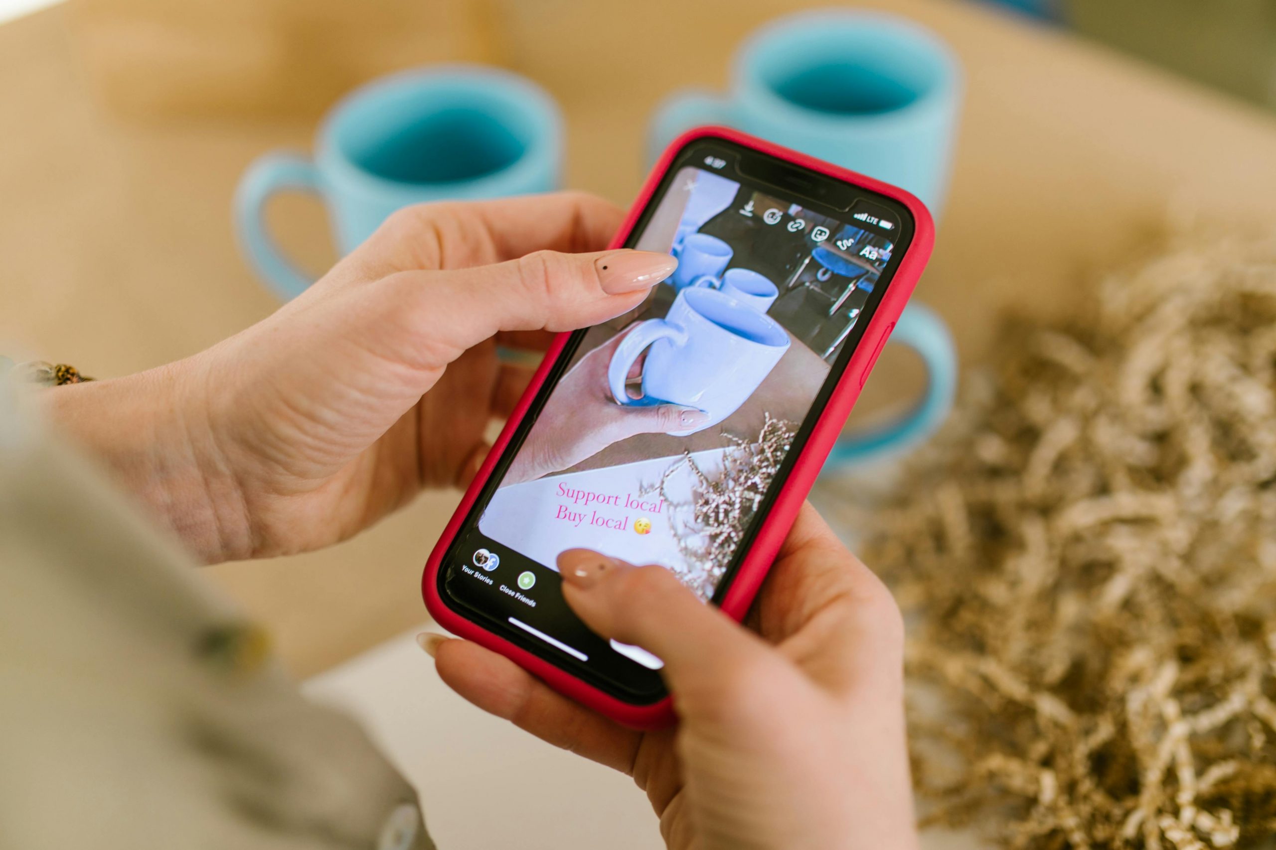 online seller using a smartphone to photograph a ceramic mug on a table